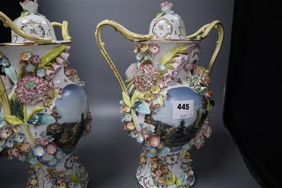 A pair of floral encrusted two handled and lidded vases